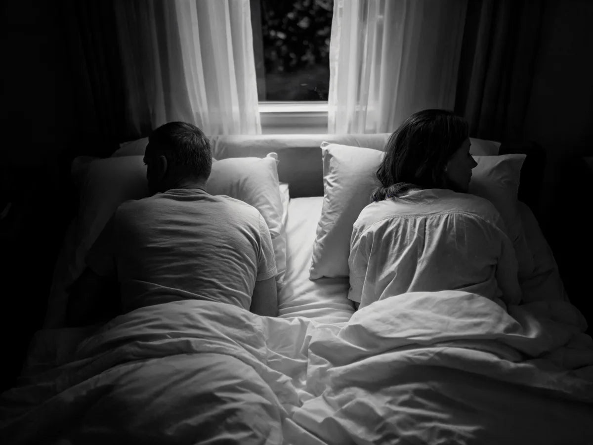 A couple lying apart in bed, both awake