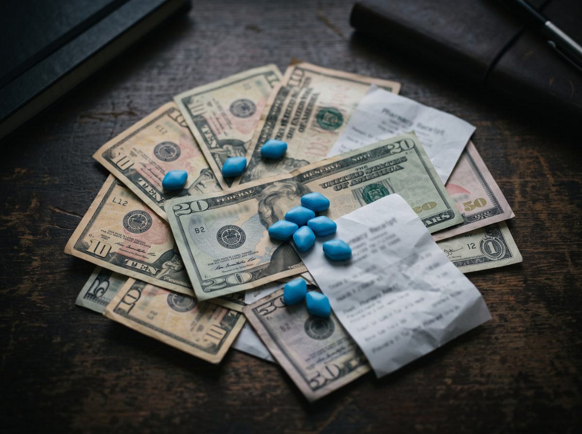 Blue pills scattered on top of cash and pharmacy receipts